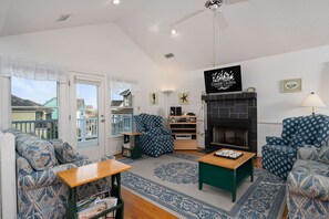A cozy living room with patterned sofas, a fireplace, and a view of the outside.