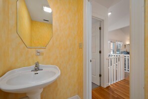 A bathroom with a white sink, a mirror, and a door leading to a balcony with a white railing.