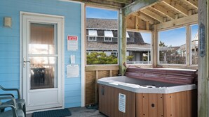 Een bubbelbadgedeelte met een houten terras, een deur met een ruitpaneel en een uitzicht op huizen achtergrond.