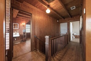 Un interior de madera con una escalera, un lavabo blanco y un ventilador.