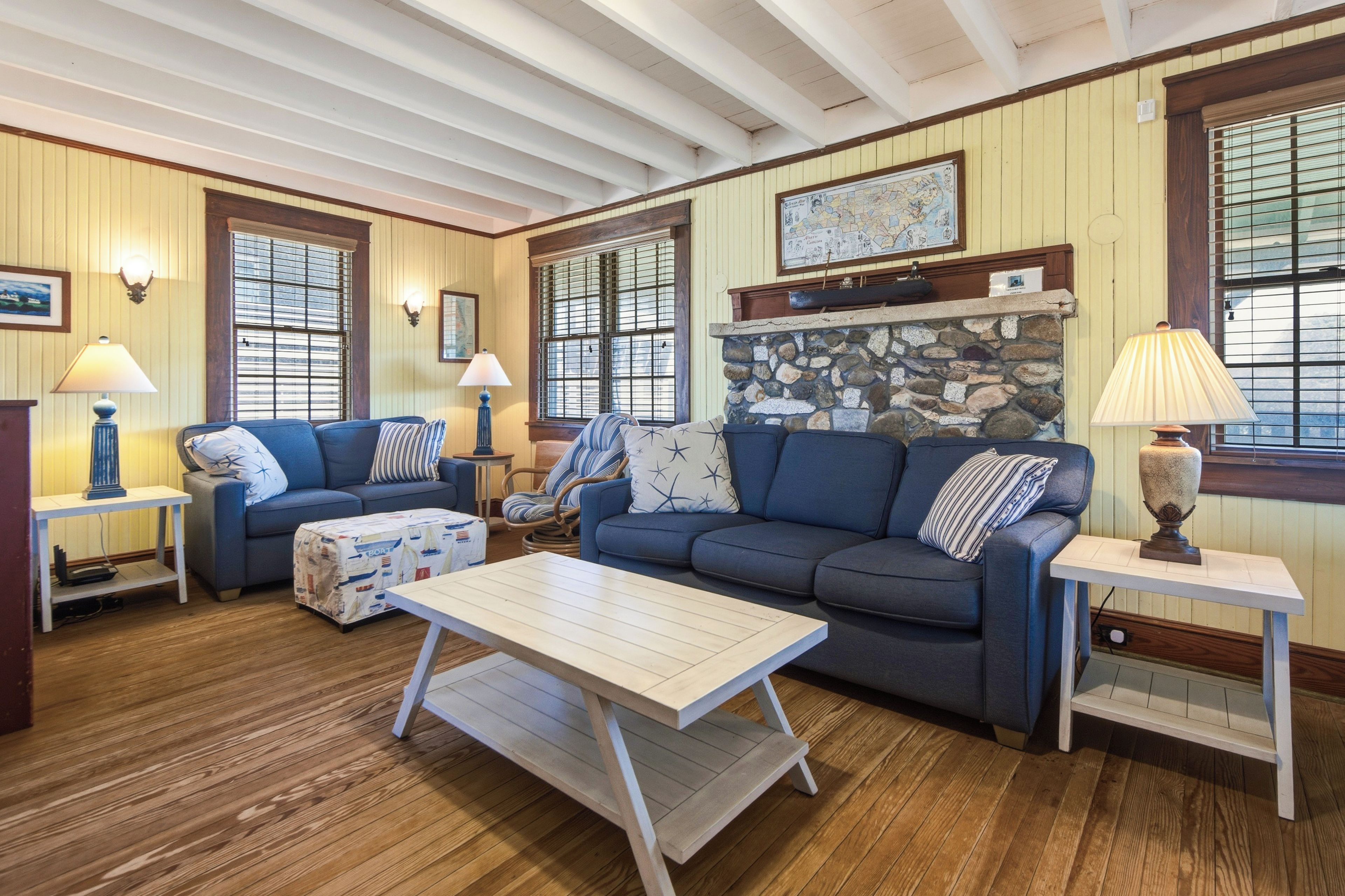 A cozy living room with a blue sofa, a wooden coffee table, and a stone fireplace.