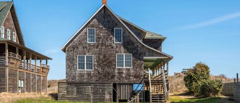 A rustic wooden building with a gabled roof, a covered porch, and a small staircase leading to a door.