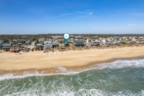 Une zone résidentielle côtière avec des maisons le long de la plage, un ciel dégagé et un marqueur de localisation indiquant la région de Coastal Carolina.