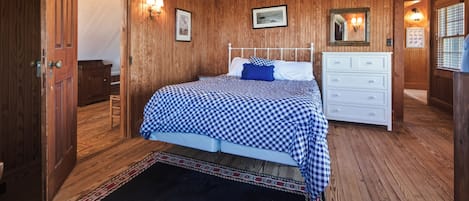 Quarto com painéis de madeira, cama, penteadeira e luminárias fixadas na parede.
