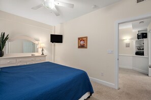 A bedroom with a bed, a dresser, a mirror, a television, and a door leading to a closet.