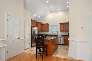 A kitchen with wooden cabinets, a stainless steel refrigerator, and a bar stool.