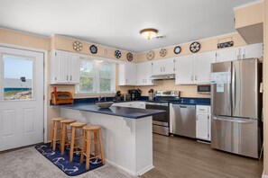 A kitchen with white cabinets, a stainless steel refrigerator, and a blue countertop. - L'il Seabreeze-Oceanfront, ocean views, awesome sunrises, steps to the beach! (Nags Head)