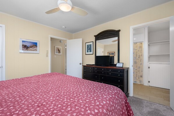 A bedroom with a bed, dresser, and a ceiling fan. - L'il Seabreeze-Oceanfront, ocean views, awesome sunrises, steps to the beach! (Nags Head)