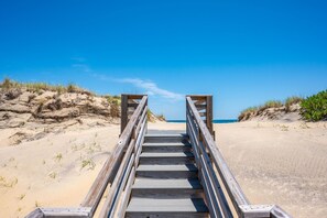 A wooden staircase leading to a beach with a clear sky.