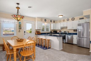 Una cocina con comedor, sillas de madera, una isla central y un refrigerador.