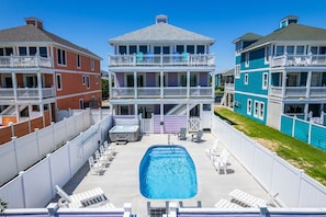 A multi-story building with a central pool surrounded by white deck chairs.