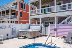 Un espace piscine avec un jacuzzi, un escalier et une terrasse entourée d’une clôture.