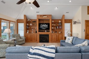 A living room with a fireplace, wooden shelving, a television, and a cozy seating area.