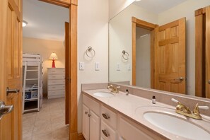 A bathroom with two sinks, a mirror, and wooden doors.