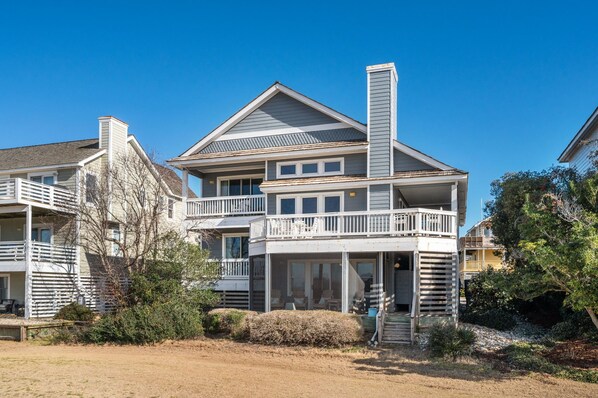 A two-story house with a balcony, a chimney, and a porch with outdoor seating.