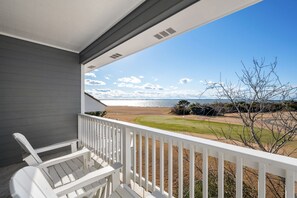 A balcony with white railings overlooking a beach and a golf course. - Sound View: Soundfront, water, golf course & great sunset views, community pool! (Nags Head)