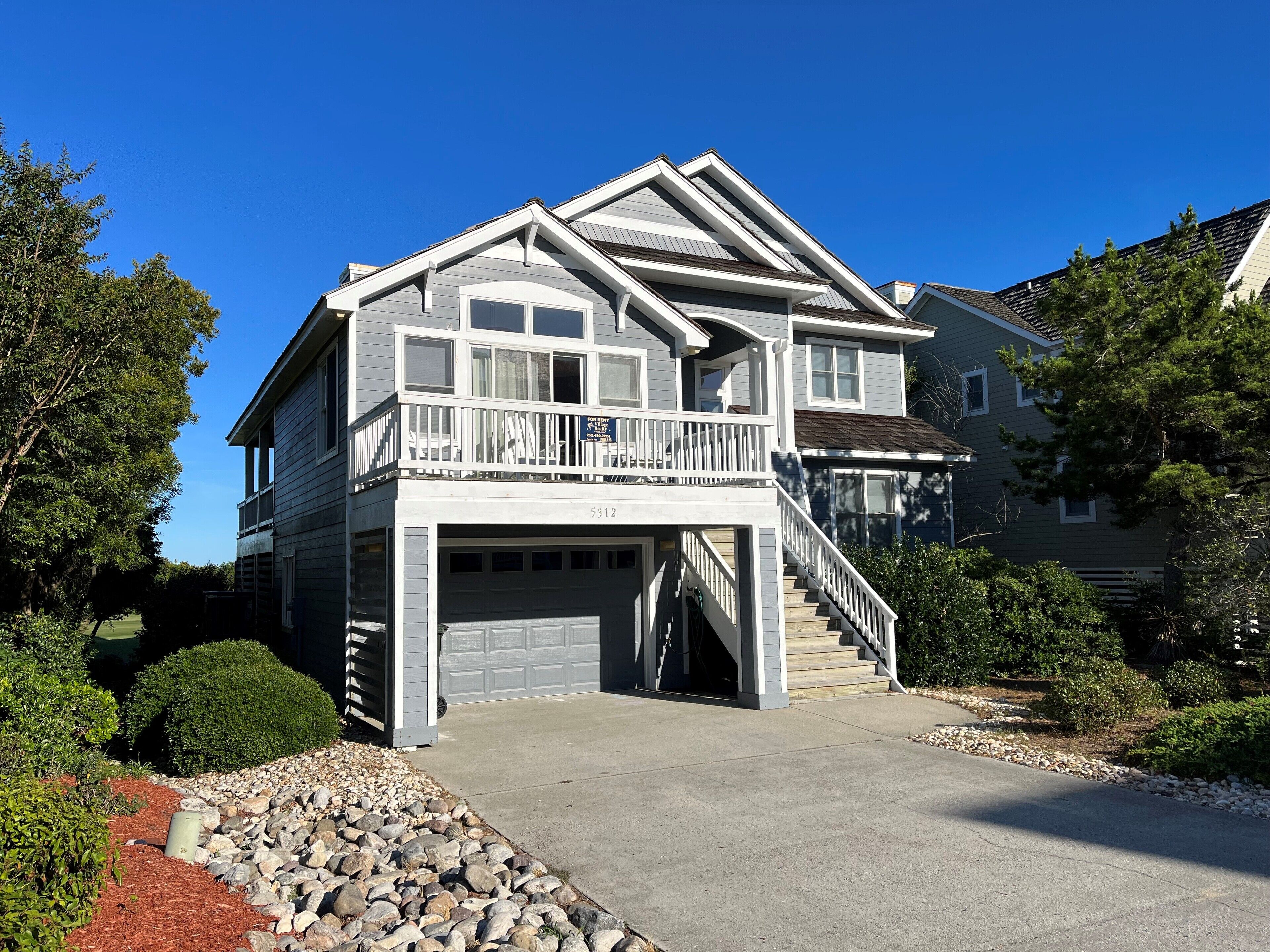 A two-story house with a front porch, a garage, and a staircase leading to the upper level.