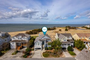 A coastal residential area with houses near the beach, a golf course, and a body of water.