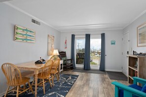 Un comedor con una mesa y sillas de madera, un tapete, y vistas al exterior a través de un ventanal.