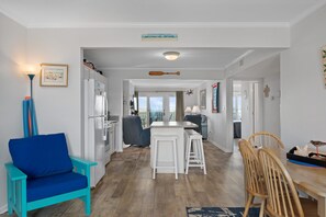Une cuisine moderne avec des meubles blancs, un coin repas avec des chaises en bois et une chaise bleue.
