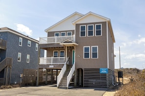 A two-story building with a balcony, a staircase, and a gated entrance.
