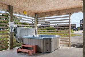 Un jacuzzi bajo una pérgola de madera, con una valla de madera al fondo.