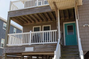 A two-story wooden house with a balcony, a green door, and a number sign '4318' on the front.