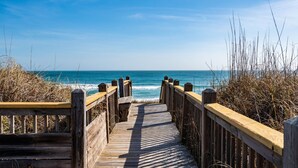 A wooden boardwalk leading to the ocean with a clear sky. - Sea Rest: Oceanfront, private walkway to beach, hot tub, YMCA access. (Nags Head)