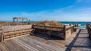 A wooden boardwalk leading to a beach with a wooden gazebo. - Sea Rest: Oceanfront, private walkway to beach, hot tub, YMCA access. (Nags Head)
