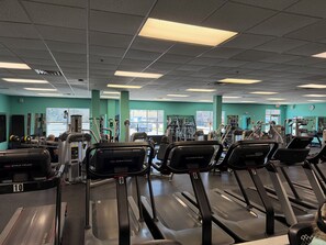 Une salle de sport équipée de tapis de course, d’appareils de musculation et d’autres équipements d’exercice.