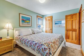 A bedroom with a bed, a nightstand, a lamp, and a door.