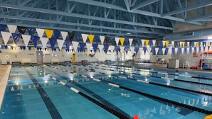An indoor swimming pool with multiple lanes, overhead beams, and safety equipment. - Sea Rest: Oceanfront, private walkway to beach, hot tub, YMCA access. (Nags Head)