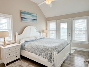 A bedroom with a bed, nightstands, a ceiling fan, and a window with blinds.