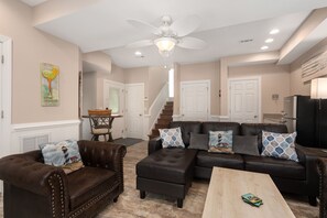 A spacious living room with a sectional sofa, two armchairs, a coffee table, and a ceiling fan.