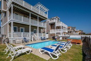 A pool area with lounge chairs and a hot tub.