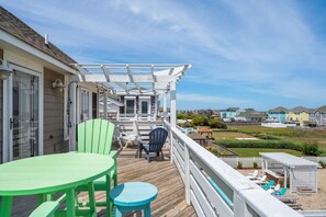 A wooden deck with outdoor furniture, a pergola, and a view of neighboring houses.