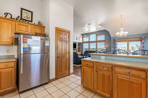 A kitchen with wooden cabinets, a stainless steel refrigerator, and a window with a view of the city.