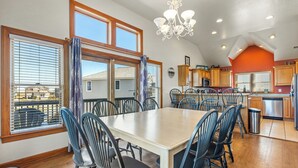 Un'ampia sala da pranzo con un tavolo e sedie di grandi dimensioni, una cucina con mobili in legno e vista panoramica attraverso ampie finestre.