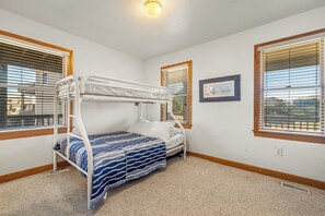 A bunk bed room with a window, a picture on the wall, and a ceiling light.