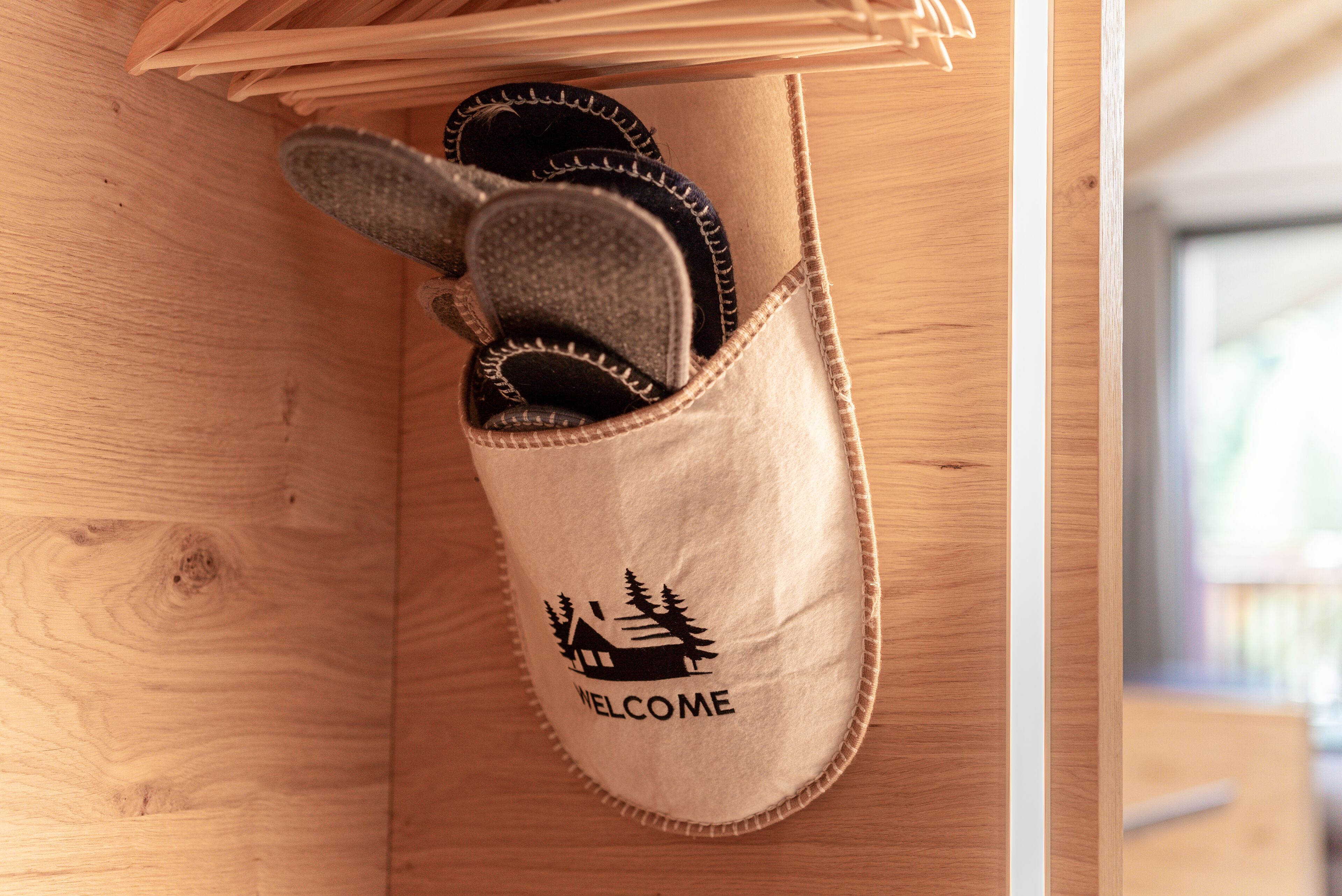 A wooden shoe rack with a pair of slippers hanging on it.