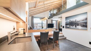 Una cocina moderna con una isla integrada, un comedor con sillas y un amplio ventanal que proporciona luz natural.