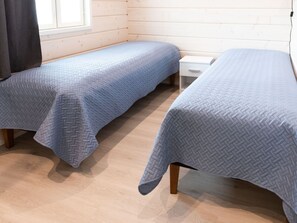 A room with two single beds, each with a quilted cover, wooden frames, and a white nightstand. - Saana 4 by Interhome (Enontekiö)