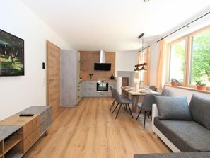 Eine moderne Wohnung mit Essbereich, Küchenzeile und einem großen Fenster mit Pflanzen.