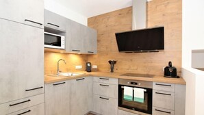 Una cucina moderna con mobili grigi, forno integrato, microonde e cappa aspirante nera.