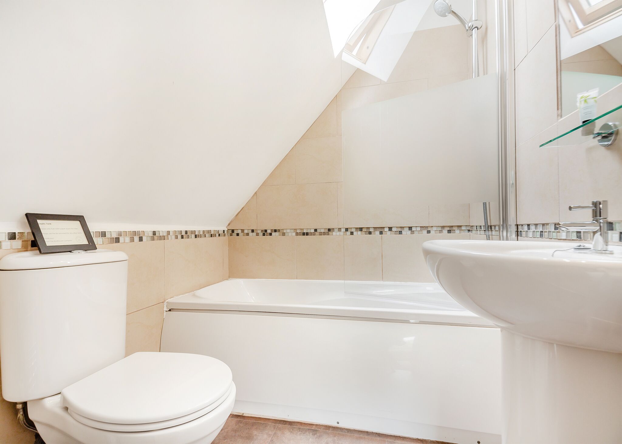 A modern bathroom with a toilet, bathtub, and sink.