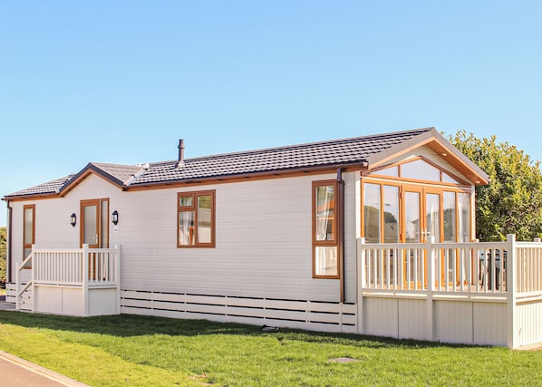 A single-story mobile home with a porch, a small deck, and a chimney.