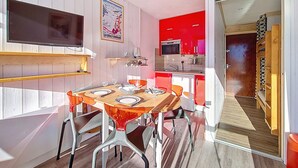 A compact kitchen with red cabinets, a microwave, and a sink. - Renovated bright studio, ski-in/ski-out, balcony, sleeps 3 (Les Menuires)