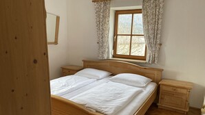 Un letto matrimoniale in legno con due comodini, una finestra con tende floreali e un pavimento in legno.