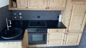 Una cucina compatta con mobili in legno, un lavandino nero, un fornello e un forno.