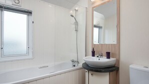 A modern bathroom with a bathtub, a sink with a mirror, and a toilet.